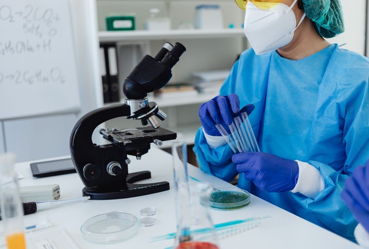 Best STD testing Houston lab technician in PPE analyzing samples with microscope and test tubes in sterile environment.