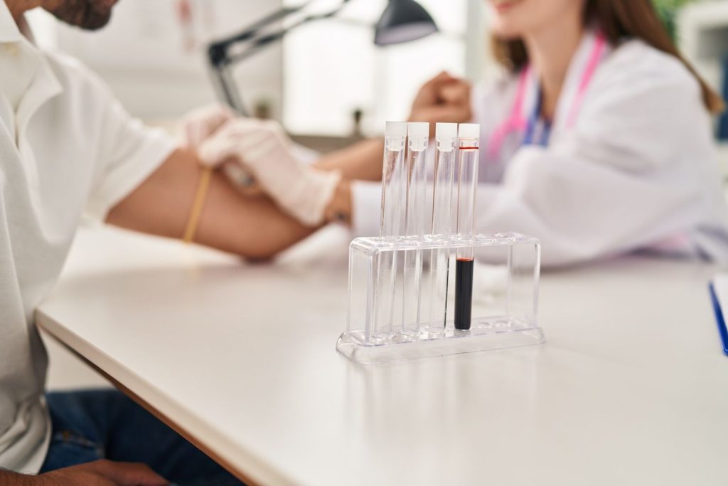 Same day STD test Houston: Lab technician drawing blood for quick STD analysis with vials on rack, providing efficient same-day results in a professional lab.