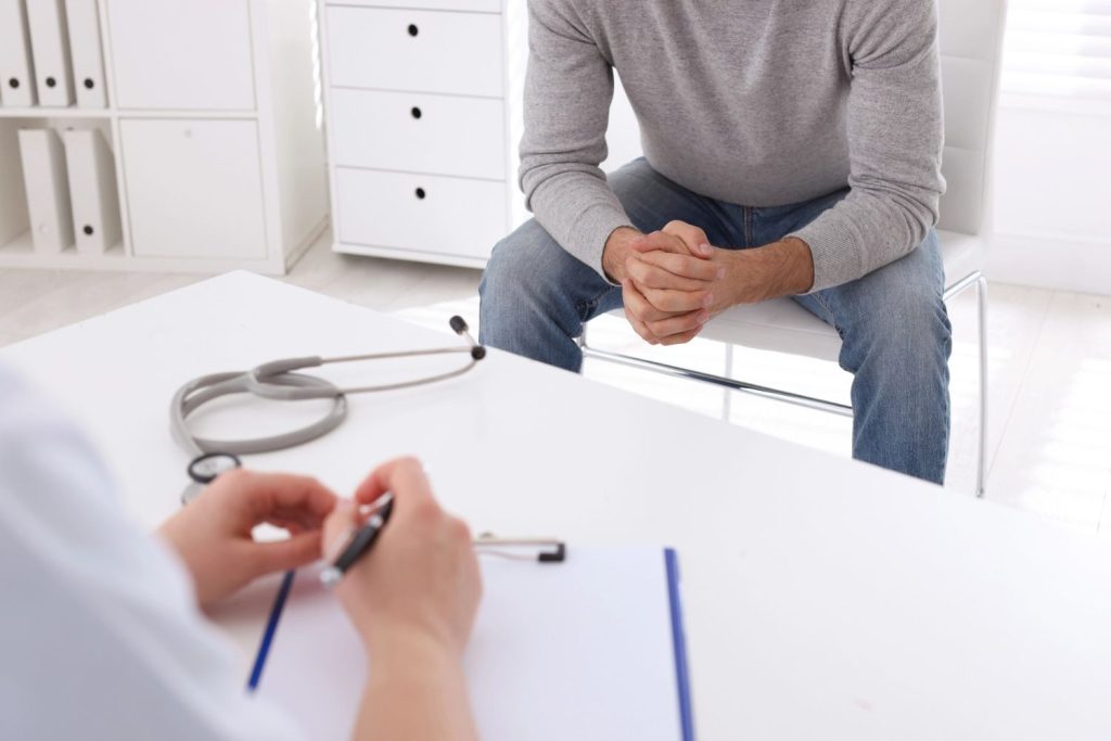 Patient awaiting results at a clinic for walk in std testing Houston while a doctor takes notes on a medical clipboard.