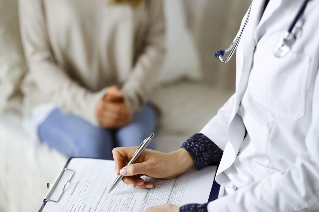 A doctor at a Houston clinic fills out medical paperwork, preparing for a same day std test during a patient visit.