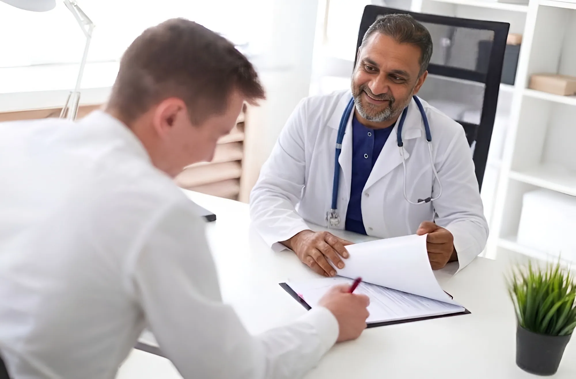 Male patient consulting Dr. Muhammad Farhan at a private clinic desk about lab reports and treatment planning